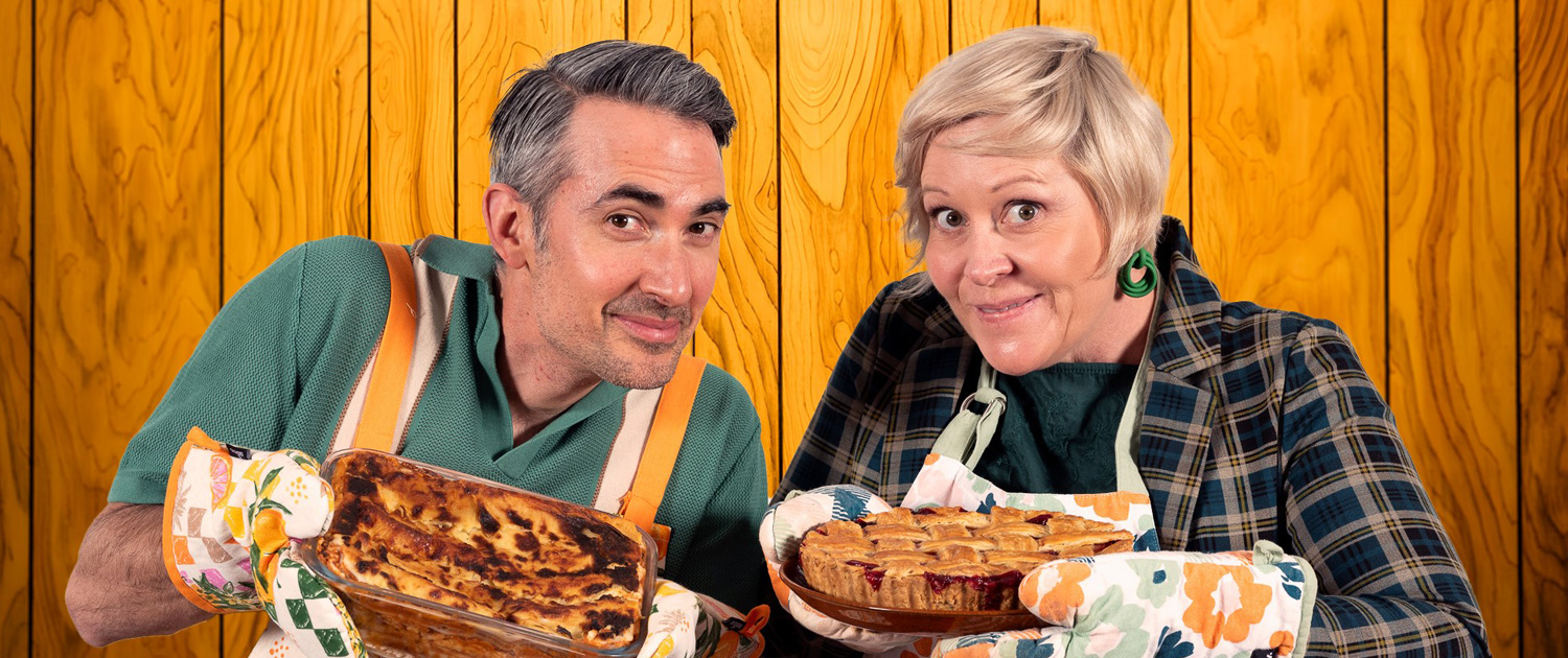 Pictured is Potluck Host Adriano Capalletta and Barefaced Stories Co-Founder Andrea Gibbs . Each are dressed in patterned aprons and are holding up sweet baked pies.